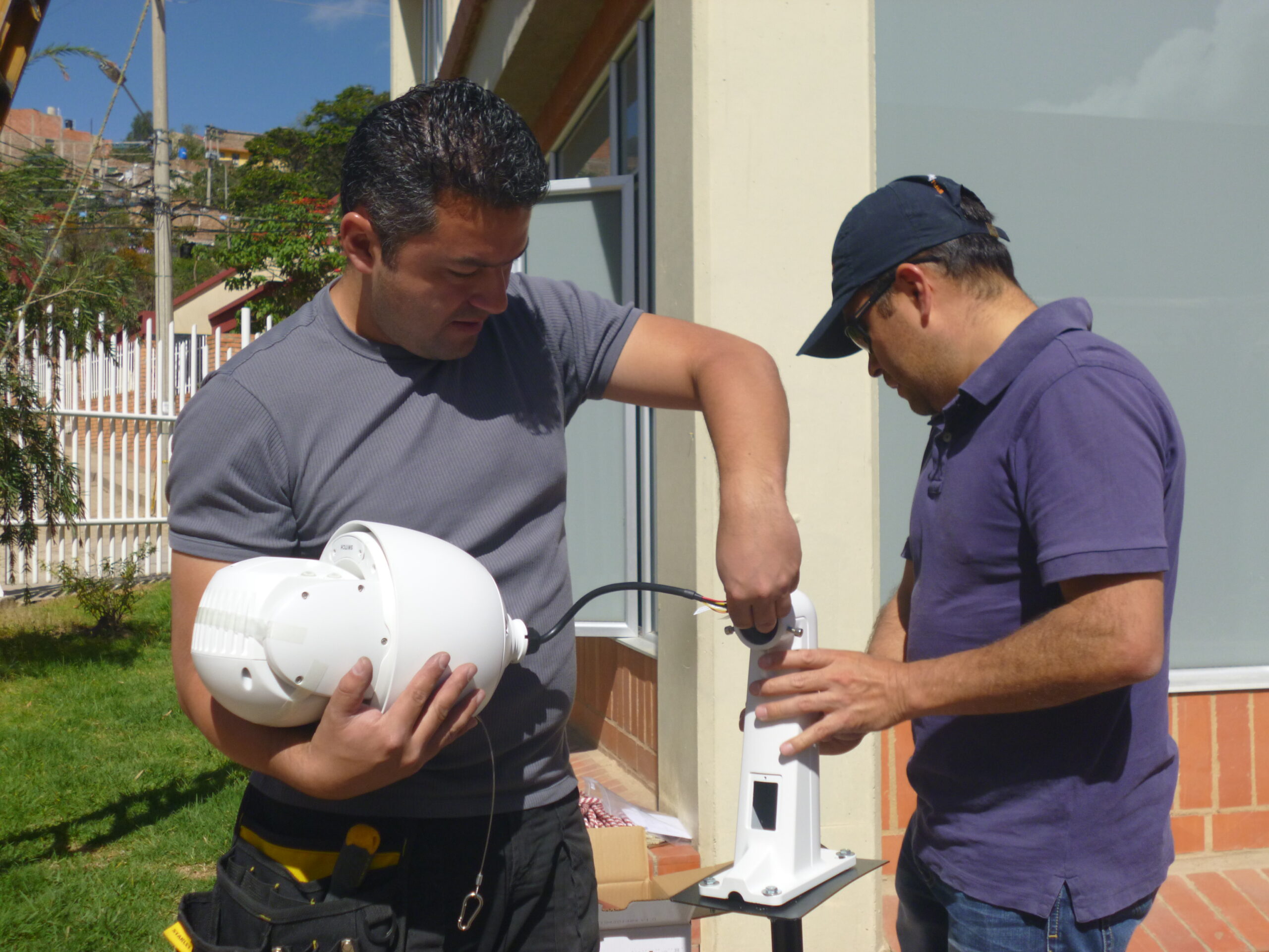 Dos instaladores especializados preparando una cámara profesional de videovigilancia en el exterior de una empresa